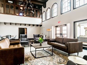 A living room with brown leather furniture and a chandelier.